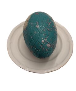Teal decorative chocolate egg with a cracked geometric pattern on a white plate.
