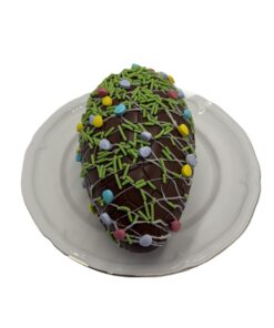 Chocolate Easter egg covered in green sprinkles and colorful candy beads on a white plate.