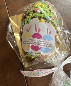 Milk chocolate Easter egg coated in colorful sprinkles, wrapped in clear plastic with a pastel bunny label filled with Cadbury mini-eggs and M&M filling.