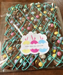 Milk chocolate bark with turquoise drizzle and pastel candy eggs in a clear package (Easter Bunny Bark).