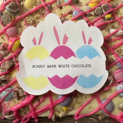 Sticker showing three pastel bunny silhouettes and the text ‘Bunny Bark White Chocolate’ over a pink-drizzled white chocolate bark surface.