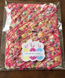 White chocolate bark decorated with pink crisscross glaze and pastel candies in clear packaging, labeled Bunny Bark White Chocolate.